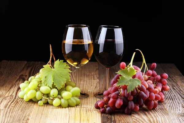 White wine and red wine in a glass with fall grapes on rustic background