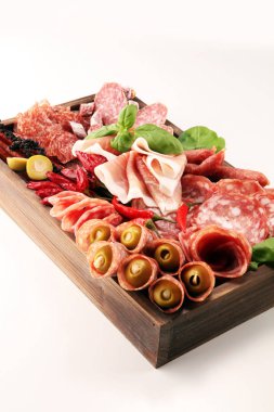 Lezzetli salam, adet dilimlenmiş jambon crudo, sosis ve fesleğen ile yemek tepsisi. Et tabağı ile seçme.