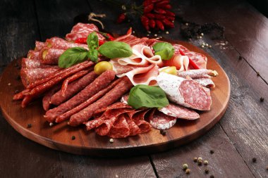 Lezzetli salam, adet dilimlenmiş jambon crudo, sosis ve fesleğen ile yemek tepsisi. Et tabağı ile seçme.
