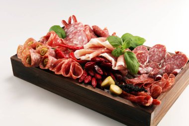 Lezzetli salam, adet dilimlenmiş jambon crudo, sosis ve fesleğen ile yemek tepsisi. Et tabağı ile seçme.