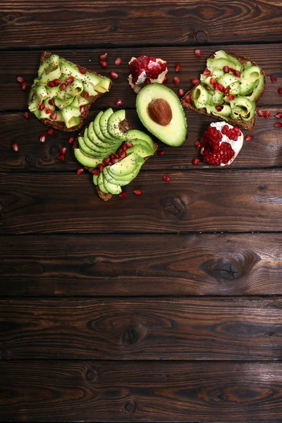 sliced avocado and ripe pomegranates on toast bread with spices and avocado