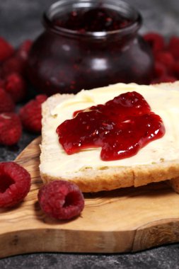 Kahvaltı veya brunch için ev yapımı ahududu reçel veya marmelat rustik tablo tost ekmeği tereyağı ile hizmet.