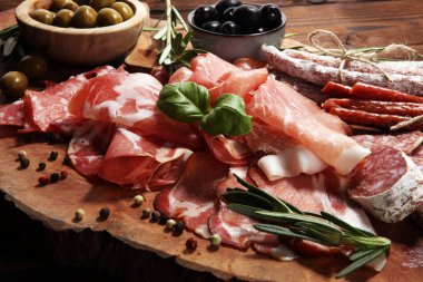 Jambon, pastırma, salam ve sosis ahşap arka plan üzerinde mermer kesme tahtası. Et tabağı meze ve zeytin