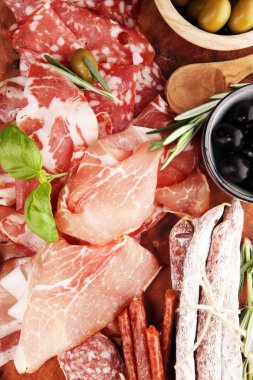 Jambon, pastırma, salam ve sosis ahşap arka plan üzerinde mermer kesme tahtası. Et tabağı meze ve zeytin