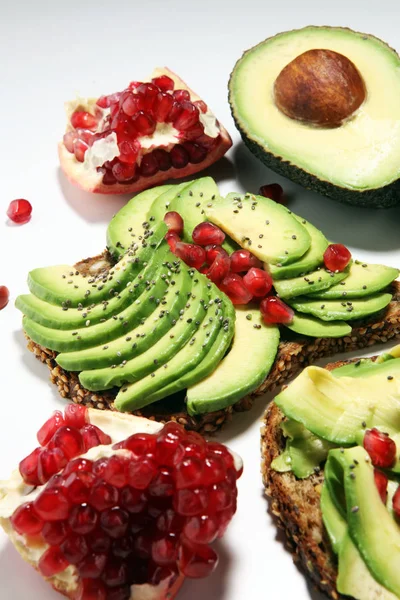 sliced avocado and ripe pomegranates on toast bread with spices and avocado