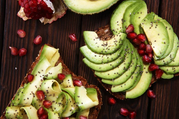 sliced avocado and ripe pomegranates on toast bread with spices and avocado