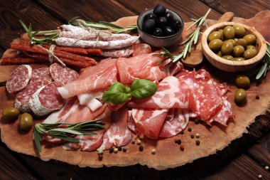 Jambon, pastırma, salam ve sosis ahşap arka plan üzerinde mermer kesme tahtası. Et tabağı meze ve zeytin