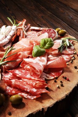 Jambon, pastırma, salam ve sosis ahşap arka plan üzerinde mermer kesme tahtası. Et tabağı meze ve zeytin