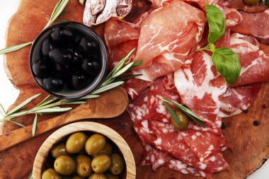 Jambon, pastırma, salam ve sosis ahşap arka plan üzerinde mermer kesme tahtası. Et tabağı meze ve zeytin