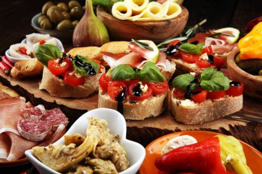 İtalyan antipasti şarap aperatifler küme. Peynir çeşitli, Akdeniz zeytin, turşu, Prosciutto di Parma, domates, enginar masada