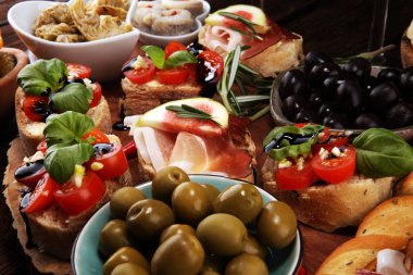 İtalyan antipasti şarap aperatifler küme. Peynir çeşitli, Akdeniz zeytin, turşu, Prosciutto di Parma, domates, enginar ve masada bardaklarda şarap