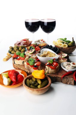 İtalyan antipasti şarap aperatifler küme. Peynir çeşitli, Akdeniz zeytin, turşu, Prosciutto di Parma, domates, enginar ve masada bardaklarda şarap