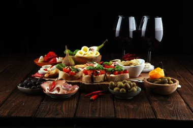 İtalyan antipasti şarap aperatifler küme. Peynir çeşitli, Akdeniz zeytin, turşu, Prosciutto di Parma, domates, enginar ve masada bardaklarda şarap