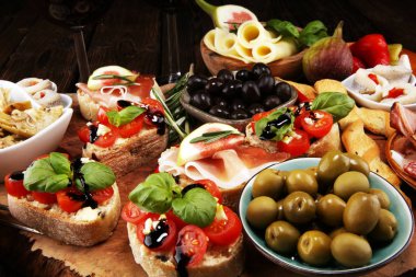 İtalyan antipasti şarap aperatifler küme. Peynir çeşitli, Akdeniz zeytin, turşu, Prosciutto di Parma, domates, enginar ve masada bardaklarda şarap