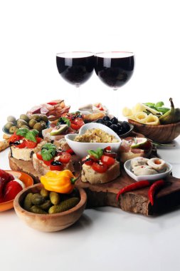 İtalyan antipasti şarap aperatifler küme. Peynir çeşitli, Akdeniz zeytin, turşu, Prosciutto di Parma, domates, enginar ve masada bardaklarda şarap