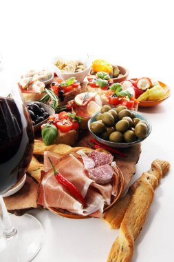 İtalyan antipasti şarap aperatifler küme. Peynir çeşitli, Akdeniz zeytin, turşu, Prosciutto di Parma, domates, enginar ve masada bardaklarda şarap