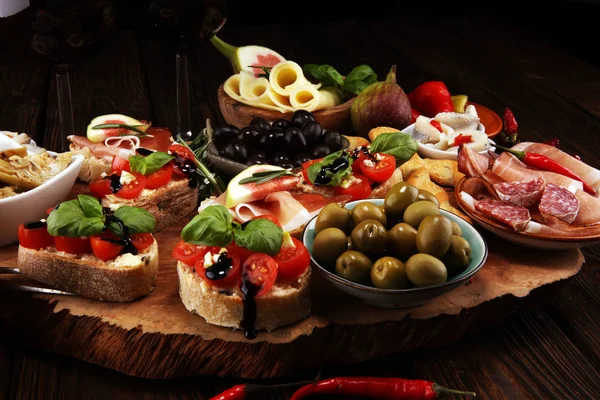 İtalyan antipasti şarap aperatifler küme. Peynir çeşitli, Akdeniz zeytin, turşu, Prosciutto di Parma, domates, enginar ve masada bardaklarda şarap