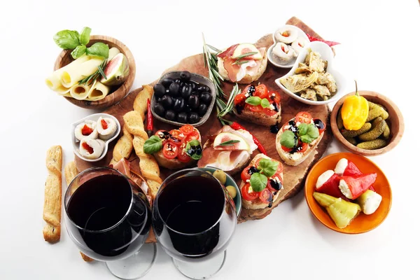 İtalyan antipasti şarap aperatifler küme. Peynir çeşitli, Akdeniz zeytin, turşu, Prosciutto di Parma, domates, enginar ve masada bardaklarda şarap