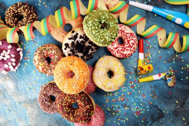 Çikolatalı buzlu, pembe sırlı ve bonibon donuts ile çeşitli çörekler. Karnaval kavramı.