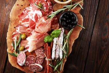 Jambon, pastırma, salam ve sosis ahşap arka plan üzerinde mermer kesme tahtası. Et tabağı meze ve zeytin