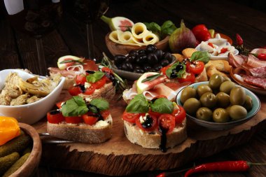 İtalyan antipasti şarap aperatifler küme. Peynir çeşitli, Akdeniz zeytin, turşu, Prosciutto di Parma, domates, enginar ve masada bardaklarda şarap