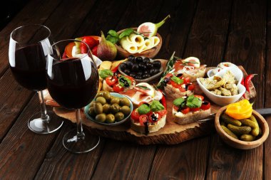 İtalyan antipasti şarap aperatifler küme. Peynir çeşitli, Akdeniz zeytin, turşu, Prosciutto di Parma, domates, enginar ve masada bardaklarda şarap