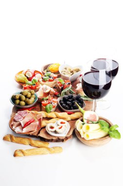 İtalyan antipasti şarap aperatifler küme. Peynir çeşitli, Akdeniz zeytin, turşu, Prosciutto di Parma, domates, enginar ve masada bardaklarda şarap