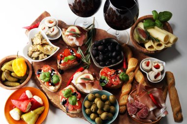 İtalyan antipasti şarap aperatifler küme. Peynir çeşitli, Akdeniz zeytin, turşu, Prosciutto di Parma, domates, enginar ve masada bardaklarda şarap