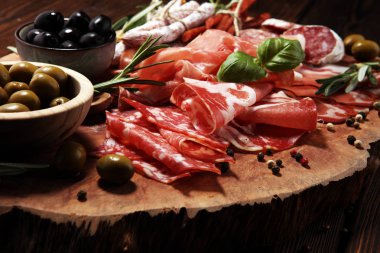 Jambon, pastırma, salam ve sosis ahşap arka plan üzerinde mermer kesme tahtası. Et tabağı meze ve zeytin