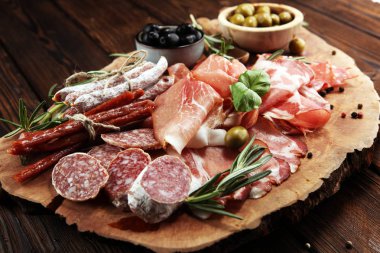 Jambon, pastırma, salam ve sosis ahşap arka plan üzerinde mermer kesme tahtası. Et tabağı meze ve zeytin