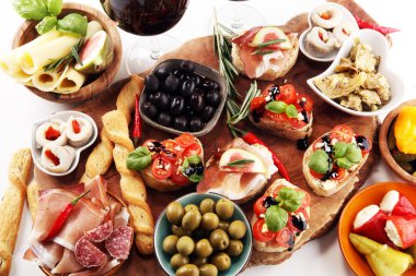 İtalyan antipasti şarap aperatifler küme. Peynir çeşitli, Akdeniz zeytin, turşu, Prosciutto di Parma, domates, enginar ve masada bardaklarda şarap