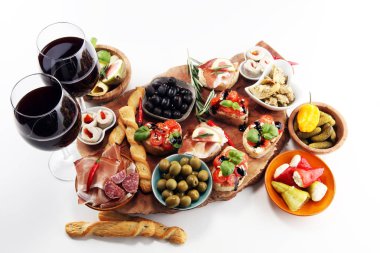İtalyan antipasti şarap aperatifler küme. Peynir çeşitli, Akdeniz zeytin, turşu, Prosciutto di Parma, domates, enginar ve masada bardaklarda şarap