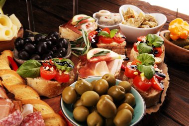 İtalyan antipasti şarap aperatifler küme. Peynir çeşitli, Akdeniz zeytin, turşu, Prosciutto di Parma, domates, enginar ve masada bardaklarda şarap