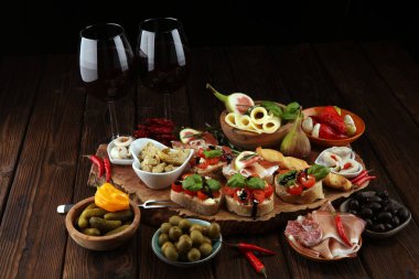 İtalyan antipasti şarap aperatifler küme. Peynir çeşitli, Akdeniz zeytin, turşu, Prosciutto di Parma, domates, enginar ve masada bardaklarda şarap
