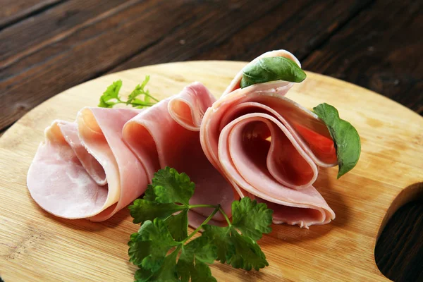 Sliced ham with parsley on table. Fresh prosciutto. Pork ham sliced snack