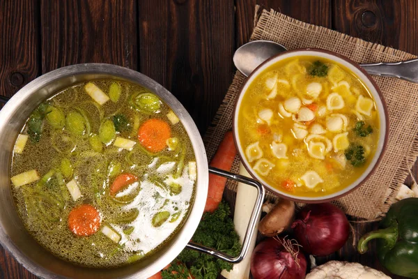Clear soup with chicken and noodles. Broth with carrots, onions various fresh vegetables in a pot. — Stock Image Clear Soup Chicken Noodles Broth Carrots Onions Various Fresh Vegetables Royalty Free Stock Photos