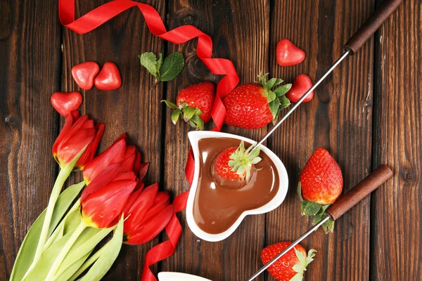 Valentine Chocolate fondue melted with fresh strawberries and dark and white chocolate. Tublips and red sugar hearts