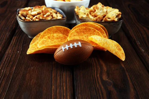 Chips, salty snacks, football on a table. Great for Bowl Game.