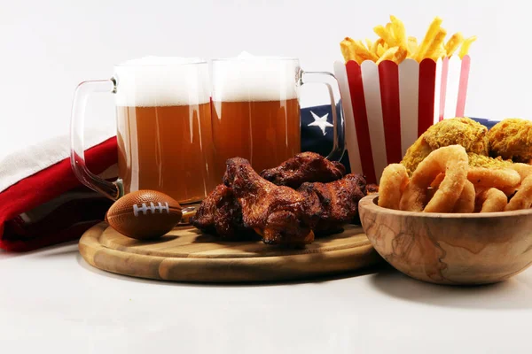 chicken wings, fries, beer and onion rings for football on a table. Great for Bowl football Game