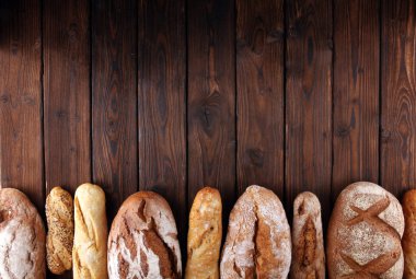 Pişmiş ekmek ve ekmek rulo ahşap masa arka plan üzerinde ürün yelpazesine. Fırın poster kavramı