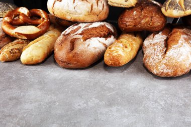 Pişmiş ekmek ve ekmek rulo taş tablo arka plan üzerinde ürün yelpazesine. Fırın poster kavramı