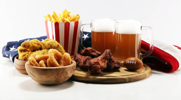 chicken wings, fries, beer and onion rings for football on a table. Great for Bowl football Game