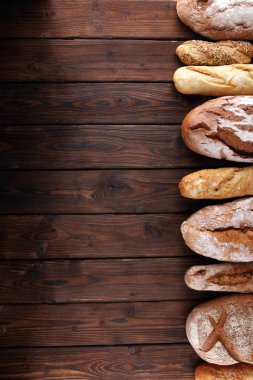 Pişmiş ekmek ve ekmek rulo ahşap masa arka plan üzerinde ürün yelpazesine. Fırın poster kavramı