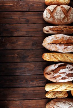 Pişmiş ekmek ve ekmek rulo ahşap masa arka plan üzerinde ürün yelpazesine. Fırın poster kavramı