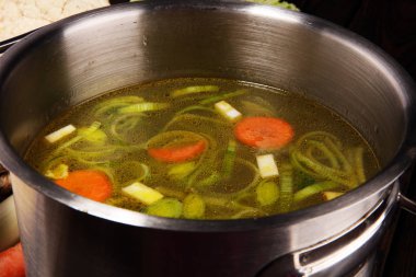 Et suyu ile havuç, soğan bir tencerede - renkli taze açık bahar çorbası çeşitli taze sebze. Kırsal mutfak sahne vejetaryen bouillon
