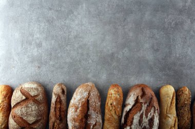 Pişmiş ekmek ve ekmek rulo taş tablo arka plan üzerinde ürün yelpazesine. Fırın poster kavramı