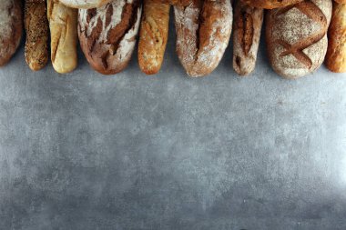 Pişmiş ekmek ve ekmek rulo taş tablo arka plan üzerinde ürün yelpazesine. Fırın poster kavramı