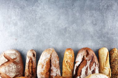 Pişmiş ekmek ve ekmek rulo taş tablo arka plan üzerinde ürün yelpazesine. Fırın poster kavramı