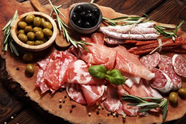 Jambon, pastırma, salam ve sosis ahşap arka plan üzerinde mermer kesme tahtası. Et tabağı meze ve zeytin