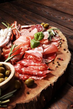 Jambon, pastırma, salam ve sosis ahşap arka plan üzerinde mermer kesme tahtası. Et tabağı meze ve zeytin